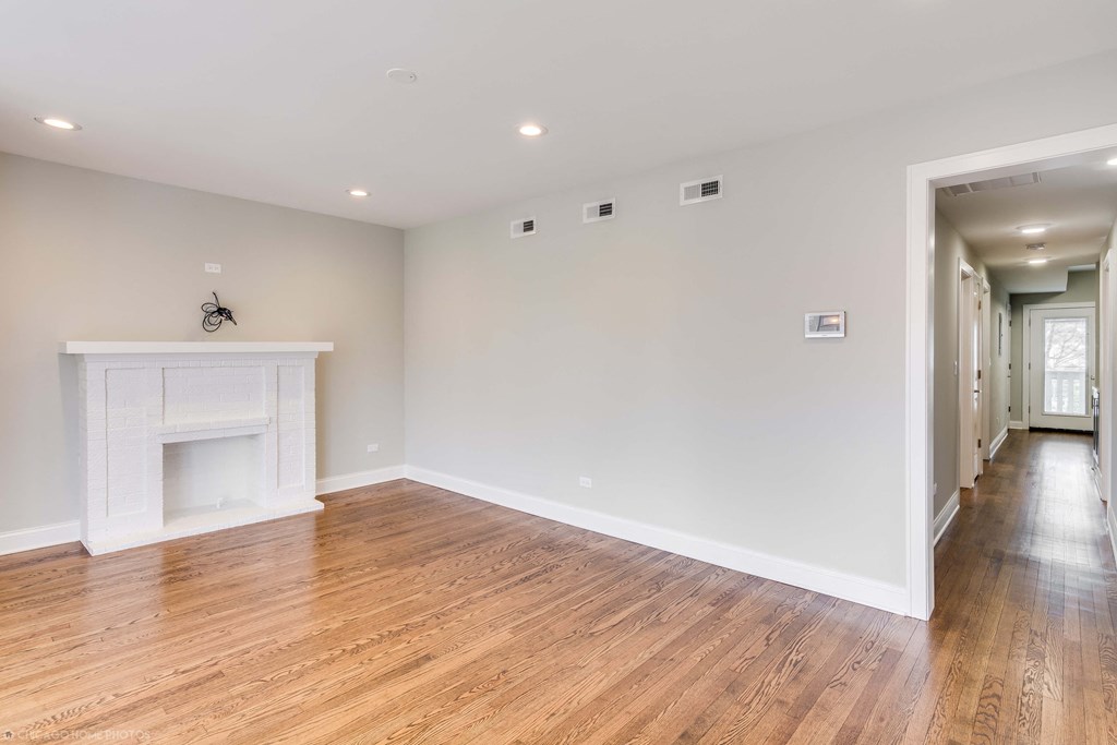a living room with white walls and a fireplace and wooden floors