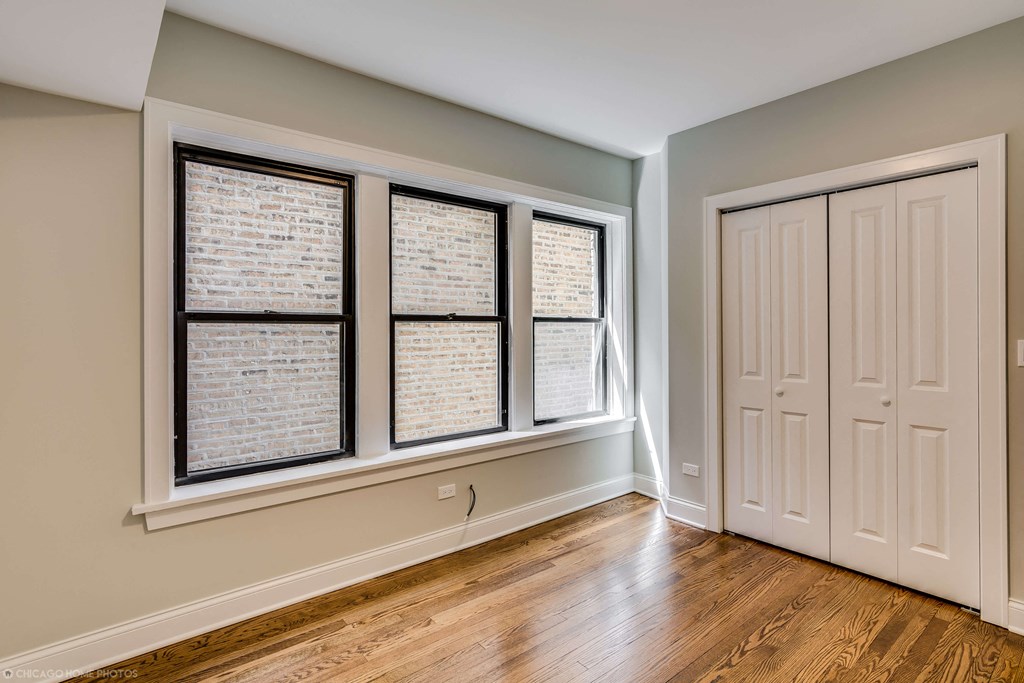 an empty living room with three windows and a door
