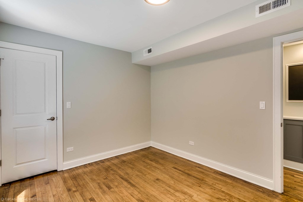 an empty room with a white door and wood flooring
