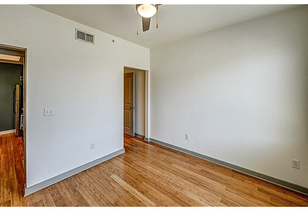an empty living room with wood floors and white walls