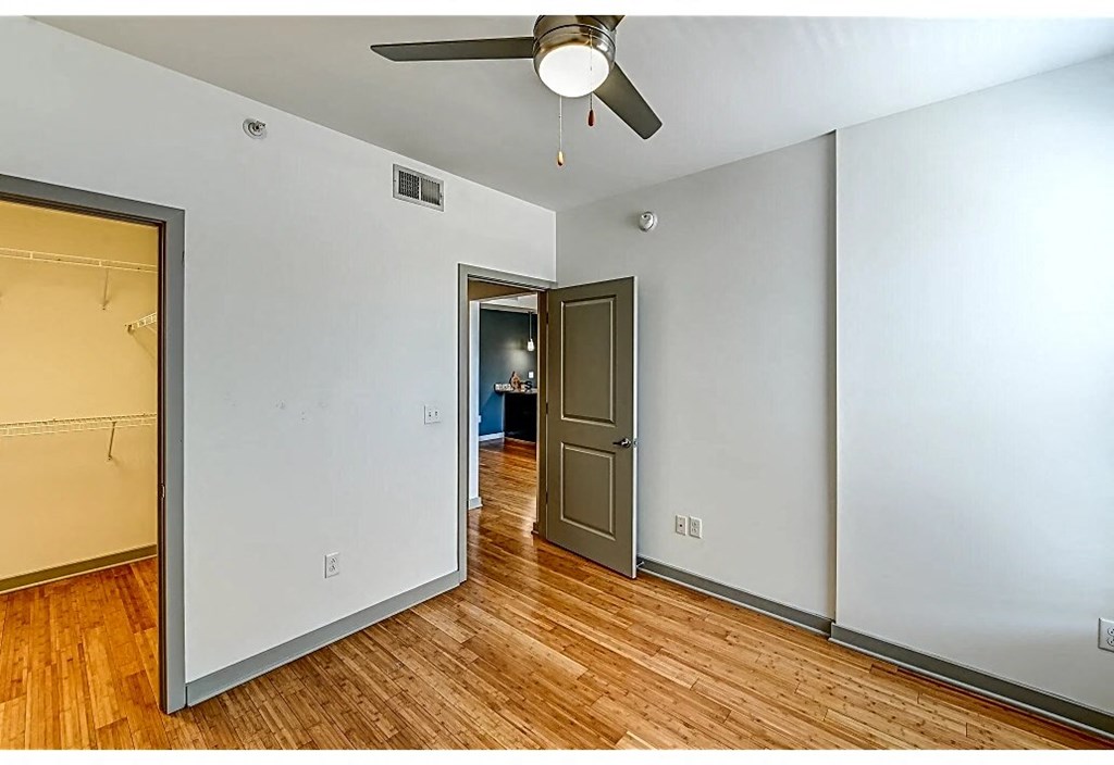 an empty room with a ceiling fan and a door to a hallway