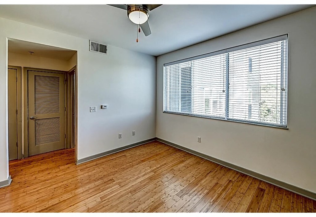 an empty living room with wood floors and a large window