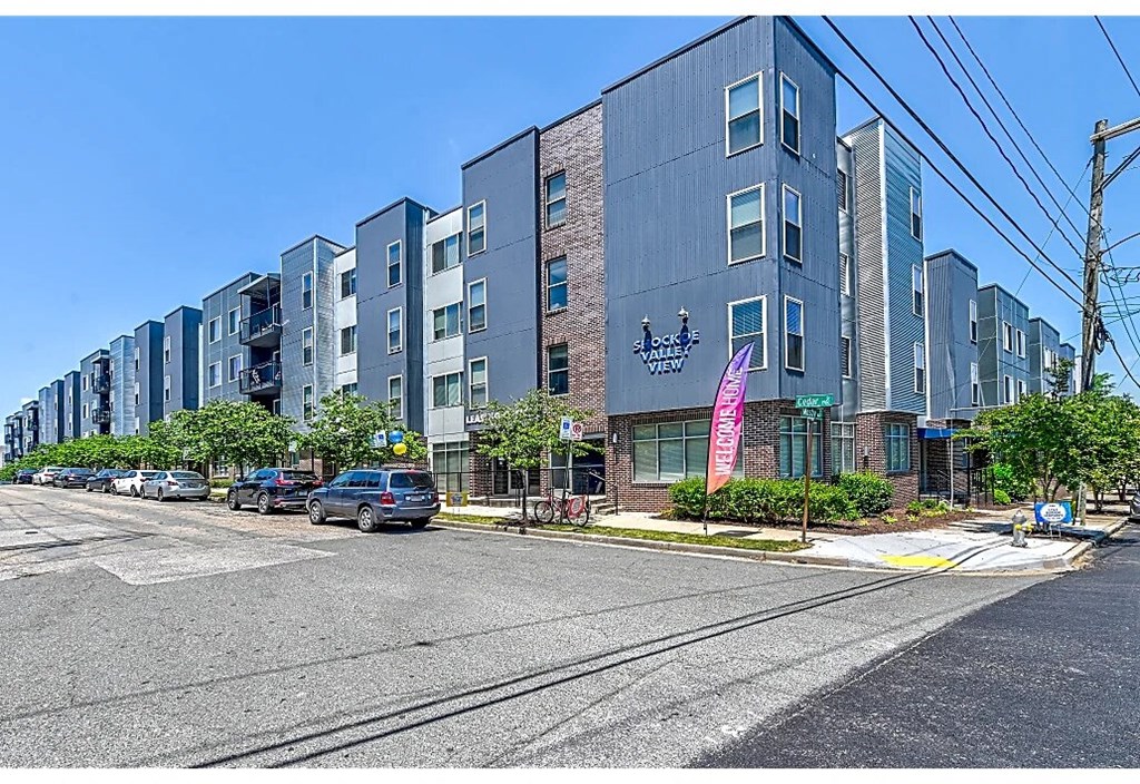 a city street with an apartment building with cars parked in front of it
