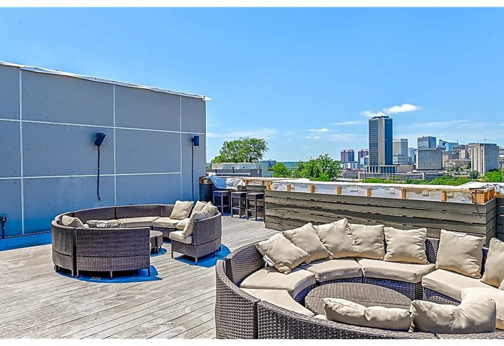 a rooftop patio with furniture and a city in the background