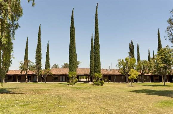 a large grass field with trees and a house