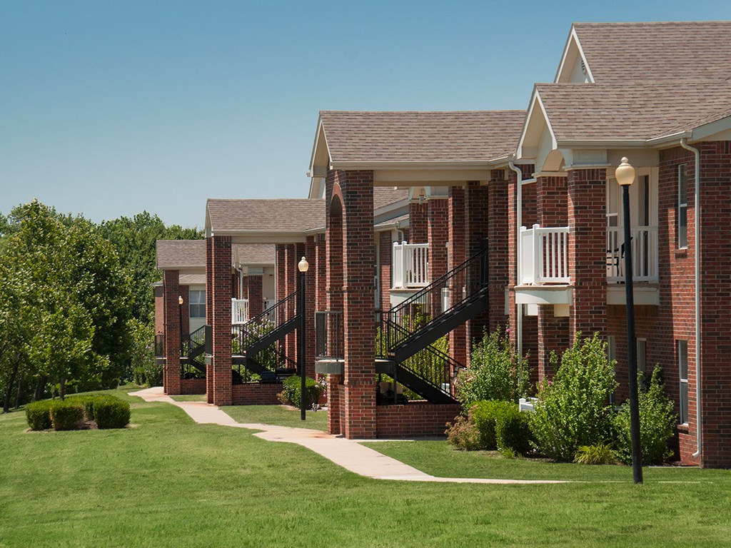 a row of brick apartment buildings on a green lawn