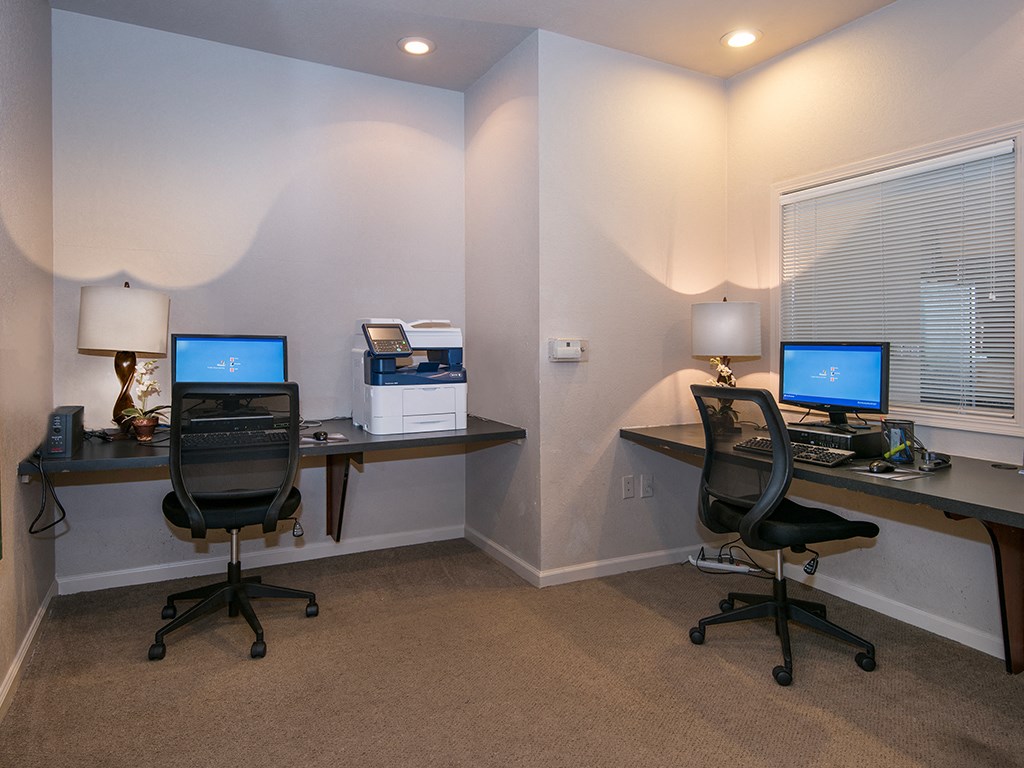two desks with computers in a room with a window