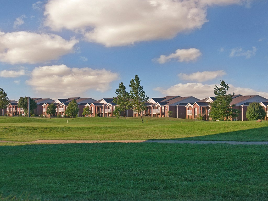 a field of green grass with houses in the background