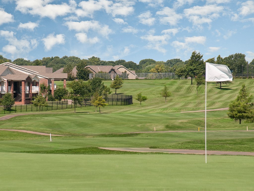 a flag flying on a golf course with houses in the background
