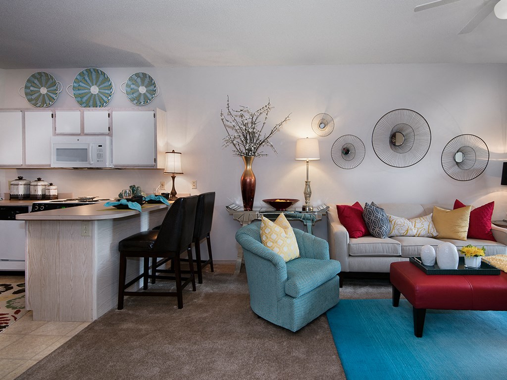 a living room with a kitchen and a couch and chairs