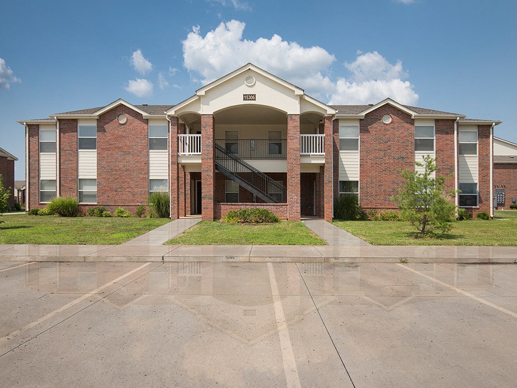 an exterior view of a brick apartment building with stairs and grass
