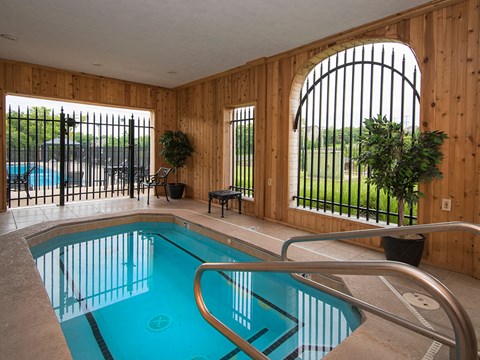 a swimming pool in a wood paneled pool house with a large window