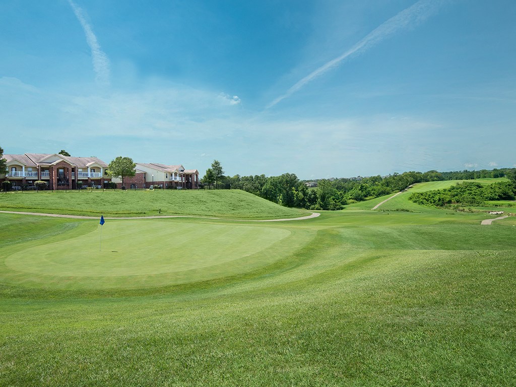a view of a golf course with houses in the background