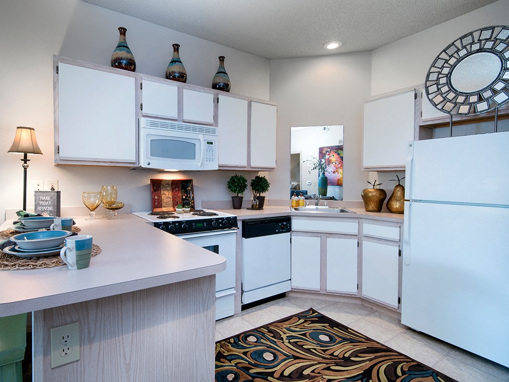 spacious kitchen with white cabinets and appliances and a large counter top