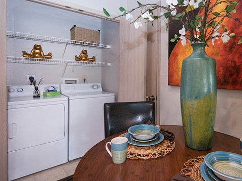 a laundry room with a table with plates and a vase of flowers