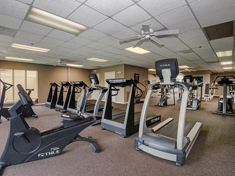 a gym with plenty of exercise equipment at the enclave at university heights