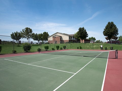 a tennis court with a house in the background