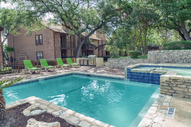 a pool with green chairs around it and a house in the background