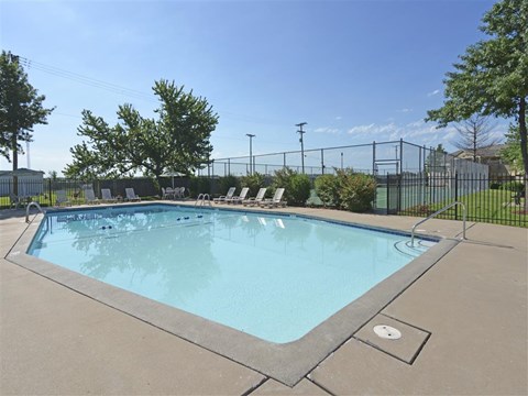 a swimming pool with chairs around it next to a fence