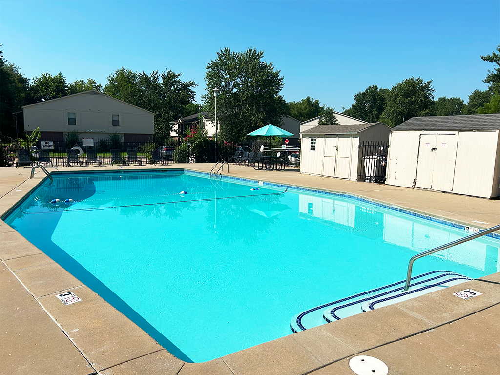 a resort style swimming pool with trees in the background