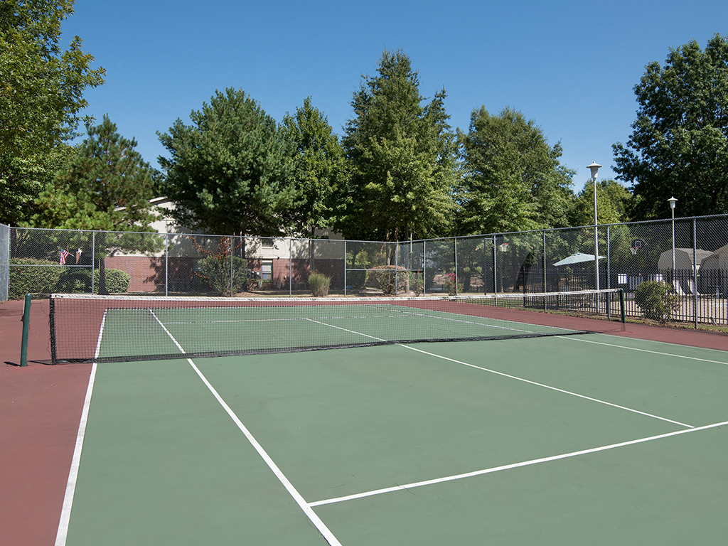 a tennis court with a fence around it and trees
