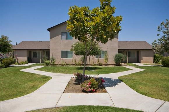 a house with a tree and a sidewalk in front of it