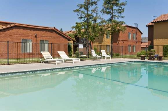 a swimming pool with white lounge chairs next to a building