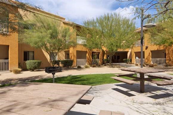 a courtyard with benches and trees in front of a building