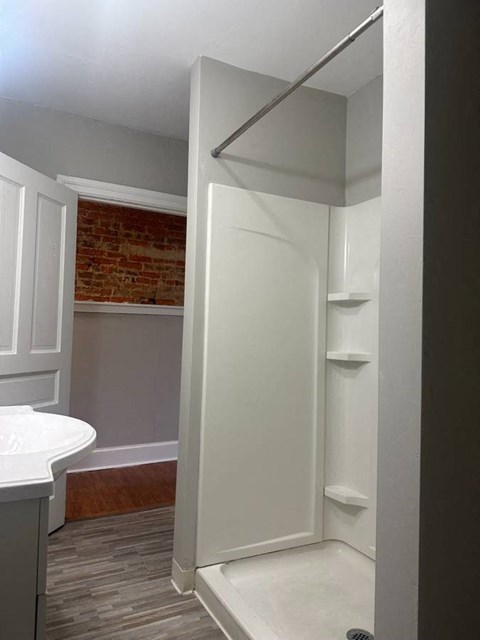 A white bathroom with a brick wall in the background.