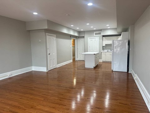 A kitchen with white appliances and wooden floors.