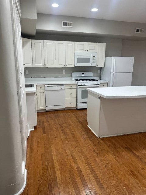 A kitchen with white cabinets and appliances.