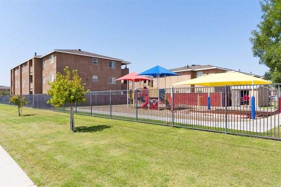 a playground with a fence and buildings in the background