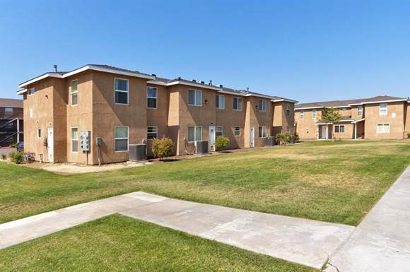 an apartment building with green grass and a blue sky