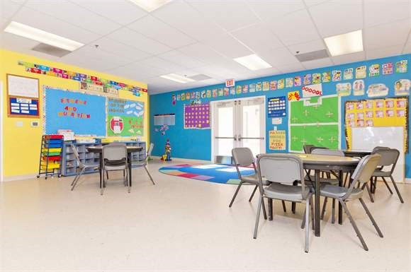 a classroom with tables and chairs and a blue wall