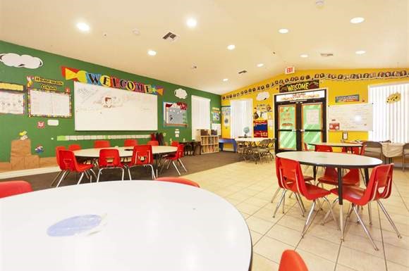 a classroom with red chairs and tables and a green wall