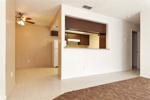 an empty living room with a ceiling fan