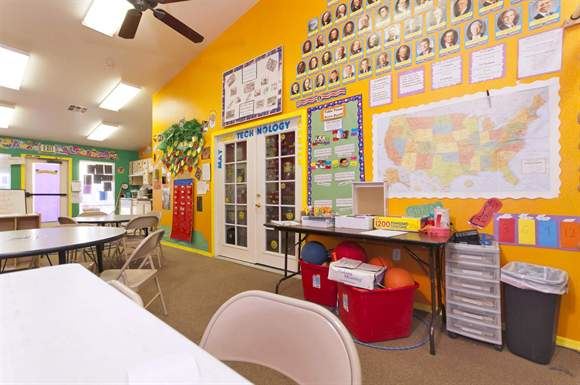 a classroom with yellow walls and white chairs