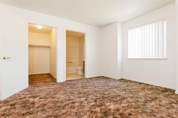 an empty living room with a door to a bathroom