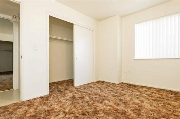 an empty bedroom with a closet and a window