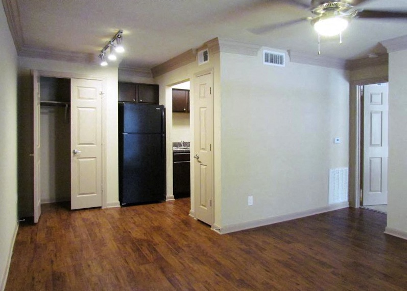 an empty living room with a black refrigerator