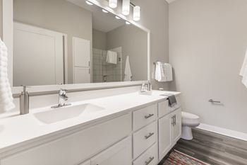 Long bathroom vanity with white cabinets and mirror above