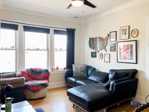 a living room with black leather furniture and three windows