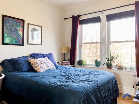 a bedroom with a blue bed and two windows