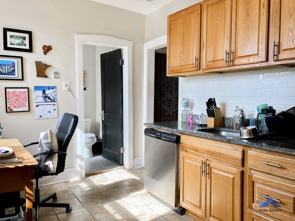 a kitchen with a desk and a sink and a door to a bathroom