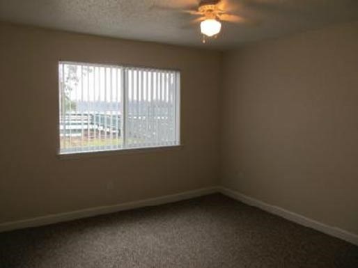 an empty bedroom with a window and a ceiling fan