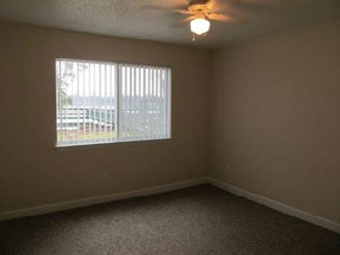 an empty bedroom with a window and a ceiling fan