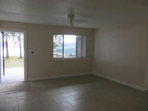 an empty living room with a window and a tiled floor