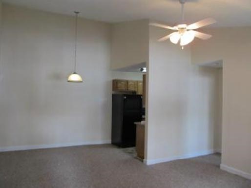 an empty living room with a ceiling fan