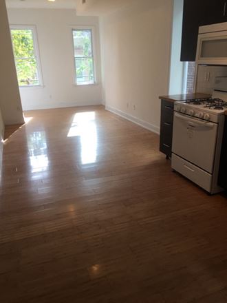 an empty kitchen and living room with wood floors