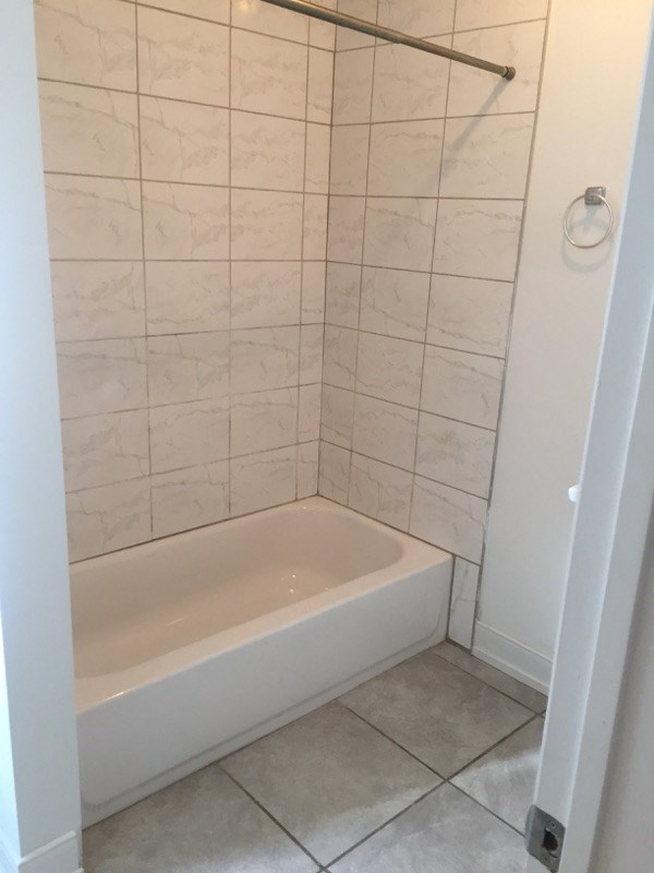 a white tiled bathroom with a tub and a shower curtain
